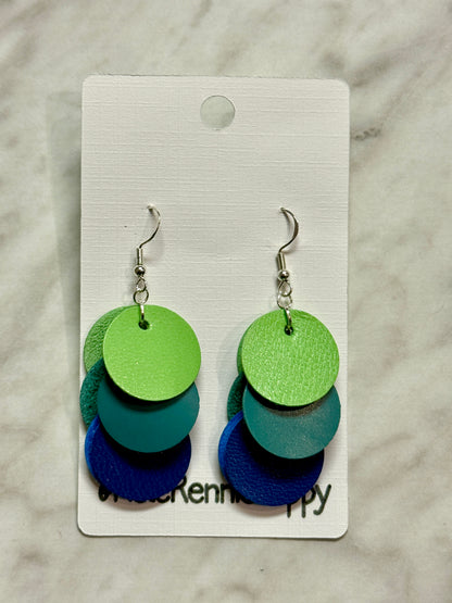 Colorful layered disc earrings on a branded card against a marble background