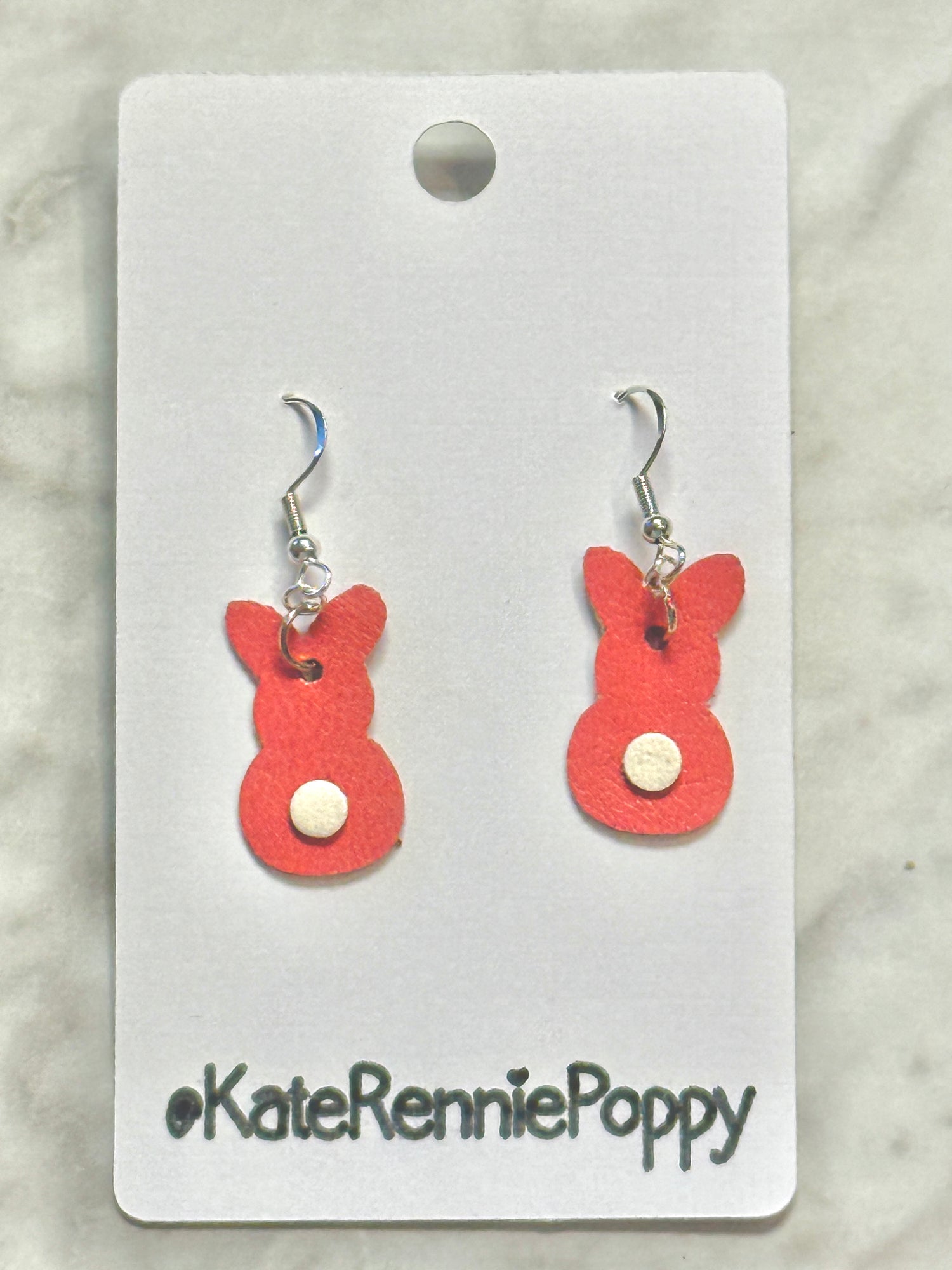 Red bunny-shaped earrings on a white card with &