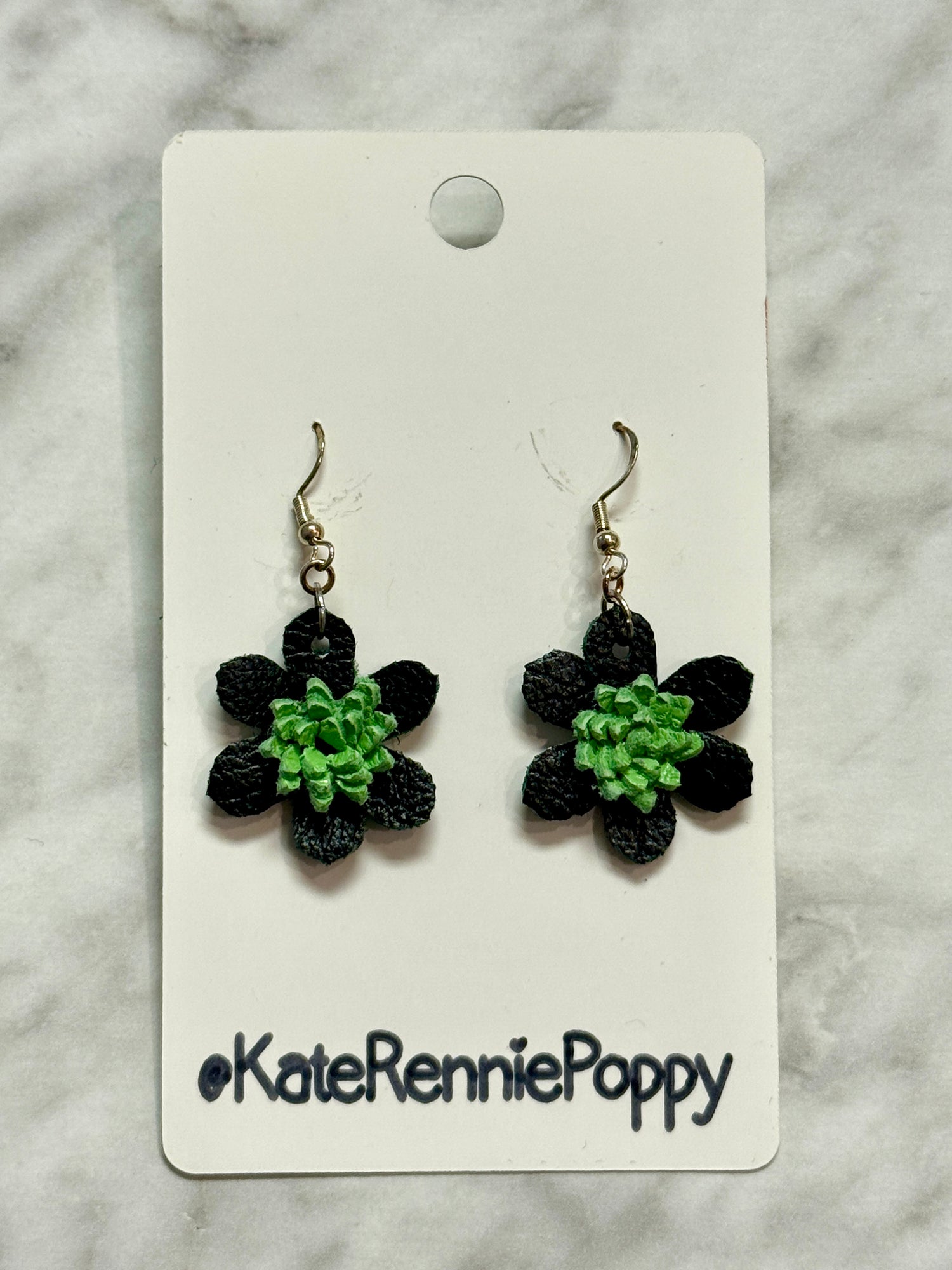 Black flower-shaped earrings on a card with &