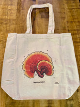The Fay Helfer Mushroom Tote Bag, made of beige eco cotton, features a reddish-brown Ganoderma lucidum mushroom illustration with handwritten labeling, shown resting on a wooden surface—an inviting nod to medicinal mushrooms.