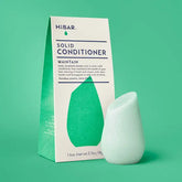 Solid conditioner bar and packaging on a green background