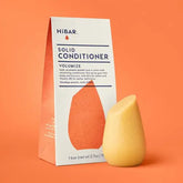 Solid conditioner bar and packaging on an orange background