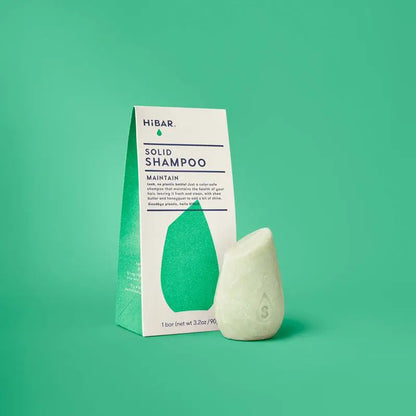 HIBAR solid shampoo bar and packaging on a green background