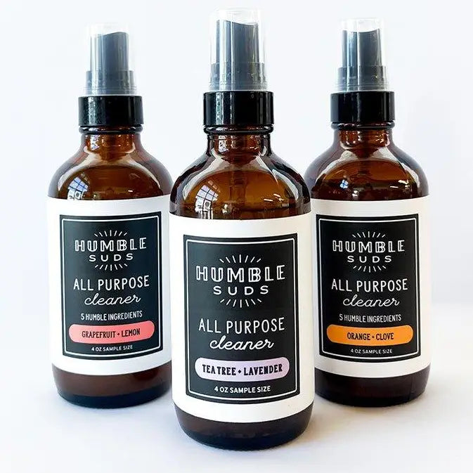 Three refillable glass bottles of Humble Suds All Purpose Cleaner in Grapefruit Lemon, Tea Tree Lavender, and Orange Clove scents, each featuring a white label.