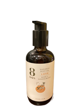 A dark amber pump bottle of 8 Days Botanicals Body Oil, 6 fl oz (177 ml), features a floral illustration and offers aromatherapy benefits for glowing skin with love, rose, and sandalwood.