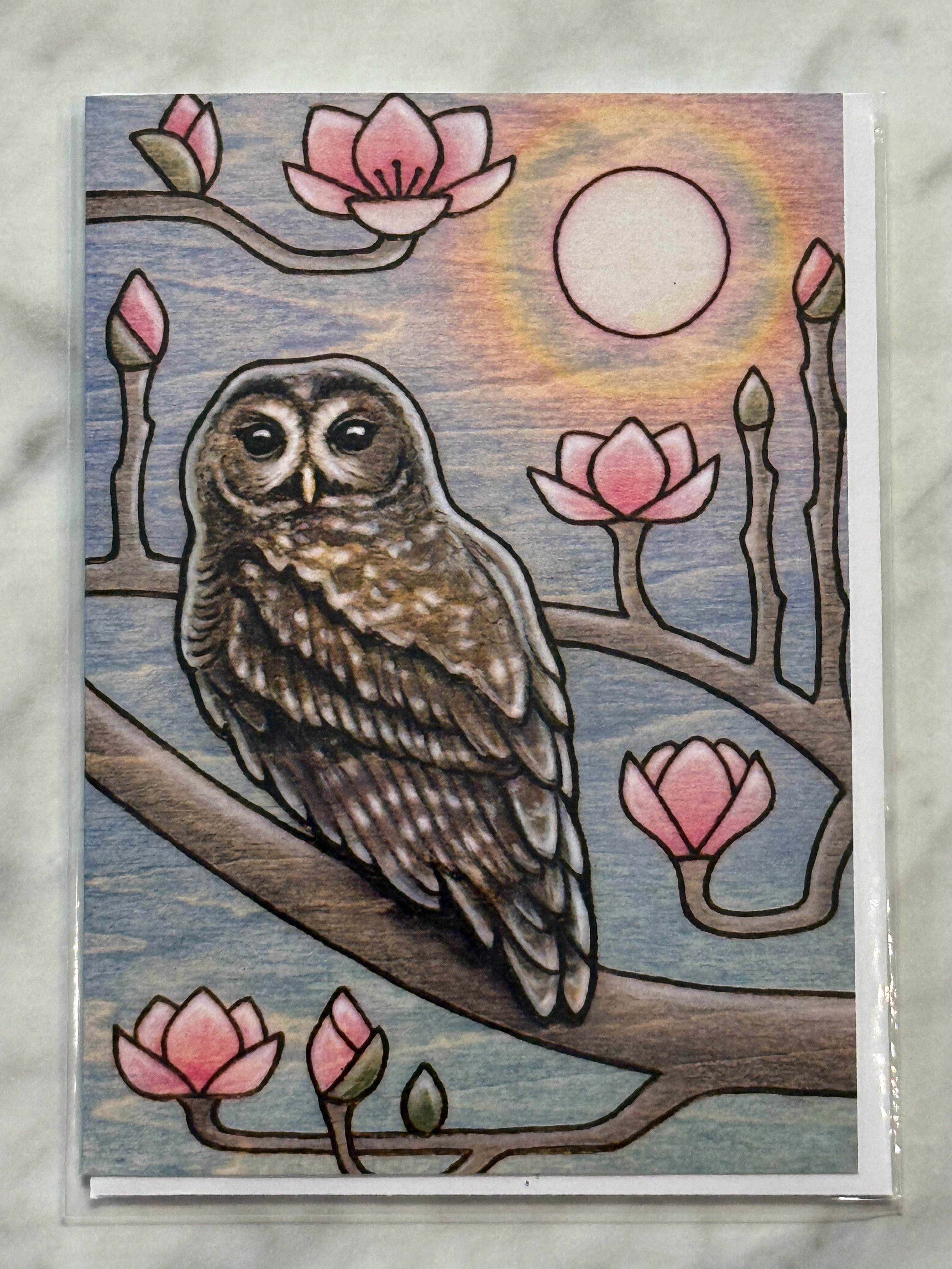 Card with an owl and magnolia blossoms design on a textured surface