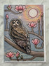 Card with an owl and magnolia blossoms design on a textured surface