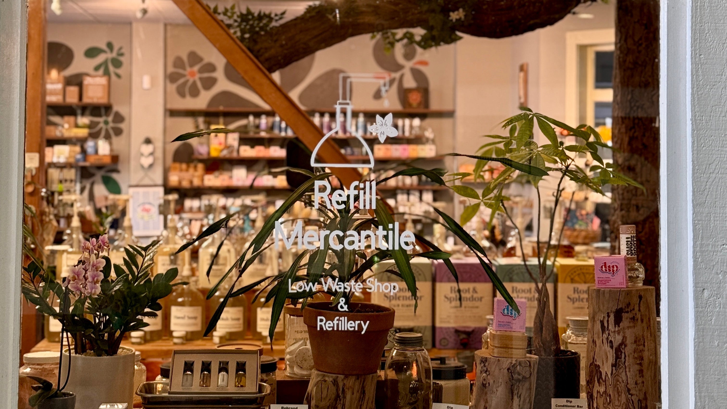 Storefront window with a view into a store sellingRefillMarcantile products.