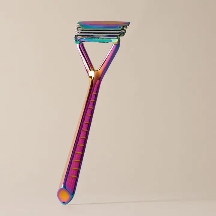 The Leaf Razor by Leaf stands upright against a plain beige background, showcasing its multicolored iridescent metallic finish. Featuring a textured handle and triple-blade head, it’s designed for plastic-free shaving.