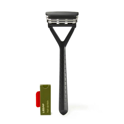 A black Leaf Razor by Leaf, featuring a textured handle, stands upright beside a green and red LEAF box with replacement blades, offering a plastic-free shave—all set on a white background.