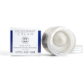 An open jar of Little Seed Farm Deodorant Cream sits next to its white box with blue accents and product details, revealing the aluminum-free cream inside.