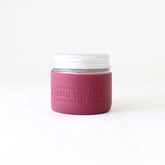 A Protective Silicone Sleeve by Little Seed Farm, featuring a white lid and mauve label, is shown against a plain white background—this sustainable alternative is good for your body and the earth.