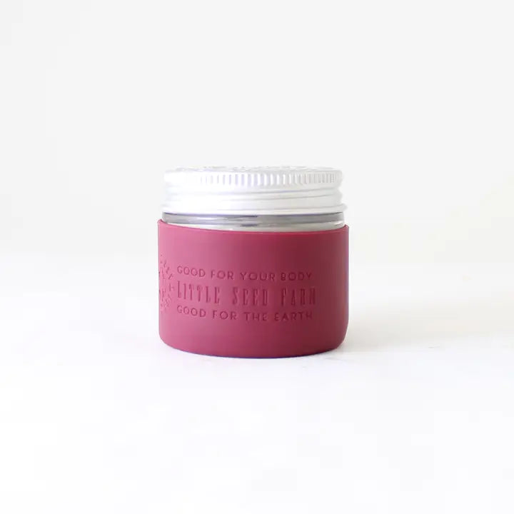 A Protective Silicone Sleeve by Little Seed Farm, featuring a white lid and mauve label, is shown against a plain white background—this sustainable alternative is good for your body and the earth.