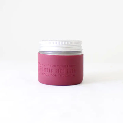 A Protective Silicone Sleeve by Little Seed Farm, featuring a white lid and mauve label, is shown against a plain white background—this sustainable alternative is good for your body and the earth.