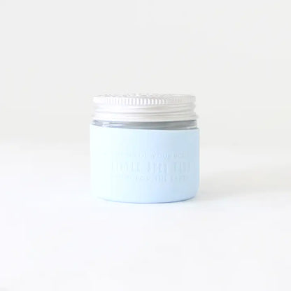 A small light blue glass jar with a white screw-on lid from Little Seed Farm sits against a plain white background, featuring a Protective Silicone Sleeve for sustainable, everyday storage.