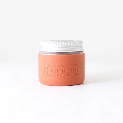 A Protective Silicone Sleeve by Little Seed Farm, featuring a sleek design and a matte orange label with sustainable messaging, is shown against a plain white background.