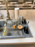 Dish rack with dishes on a kitchen counter next to a sink.