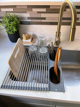 Kitchen sink area with drying rack, cutting board, and utensils.