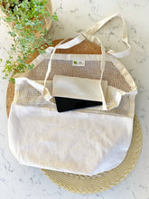 Mesh shopping bag with white fabric pocket on a woven mat