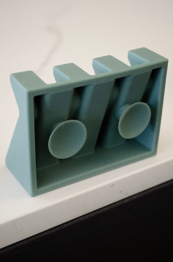 Green silicone soap dish with multiple slots and two suction cups on a white surface