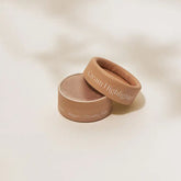 An open Mini Cream Blush and Highlighter by Minori reveals a shimmery cream inside its small round container with a beige lid. The product is vegan, cruelty-free, and ideal for sustainable beauty routines.