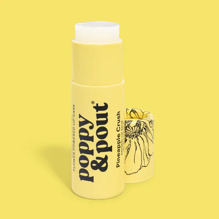 A yellow tube of Poppy &amp; Pout Lip Balm stands upright with the cap removed to reveal the balm inside. The cap, set next to it, displays a black floral illustration. The scene is set against a solid yellow background.