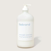 A clear pump bottle labeled Rebrand holds Bulk Face Sunscreen SPF 30, a refillable mineral sunscreen with zinc oxide and broad spectrum protection, shown against a plain light background.