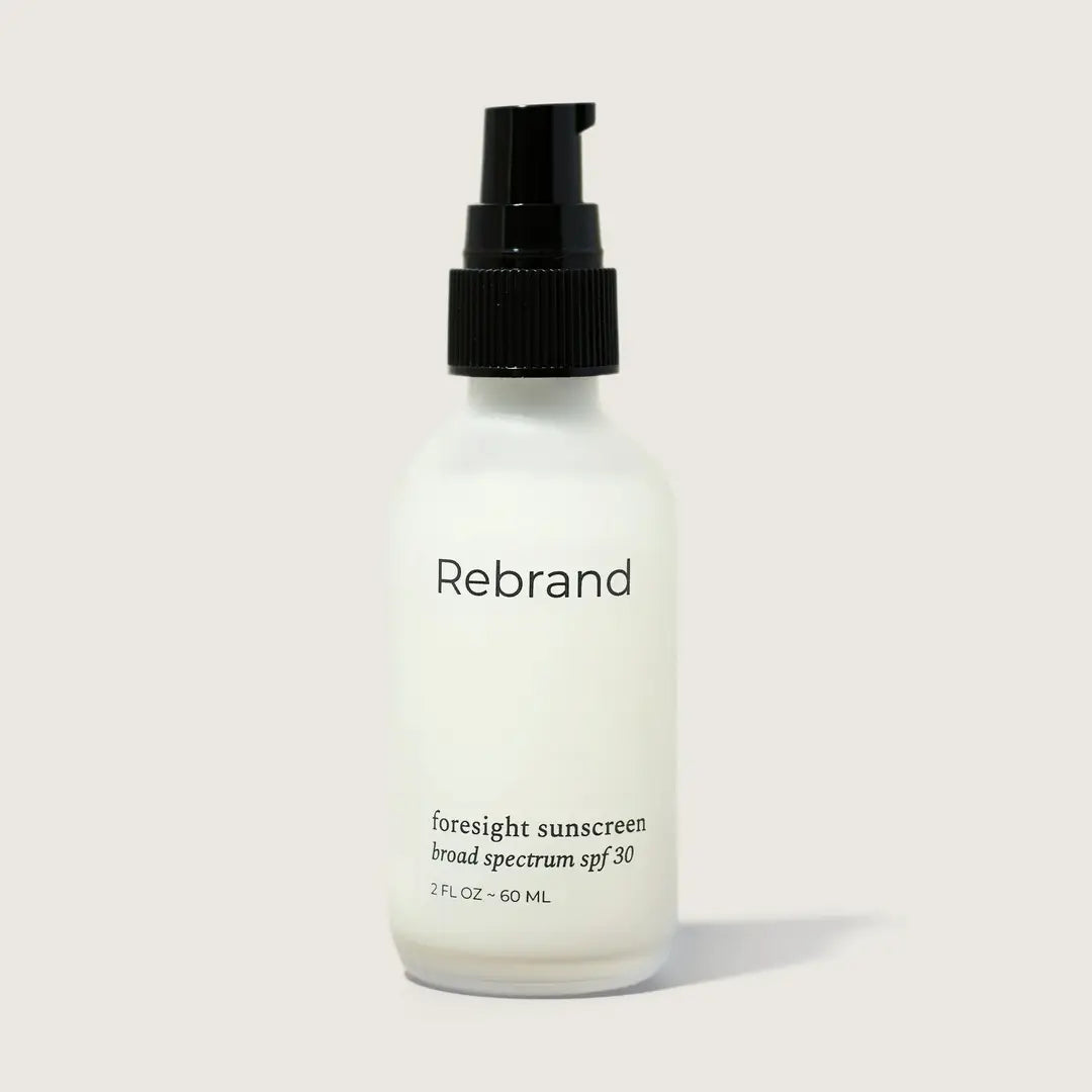 A white bottle with black pump labeled Rebrand Foresight Sunscreen SPF 30 - Mineral Sunscreen for Face, 2 fl oz (60 ml), featuring non-nano zinc oxide, on a light gray background.