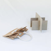 The Simple Ecology Reusable Jar Carrier, in beige glass jar tote style with organic cotton handles, lies flat beside a cardboard insert for compartment creation. Both items are displayed on a plain white background.
