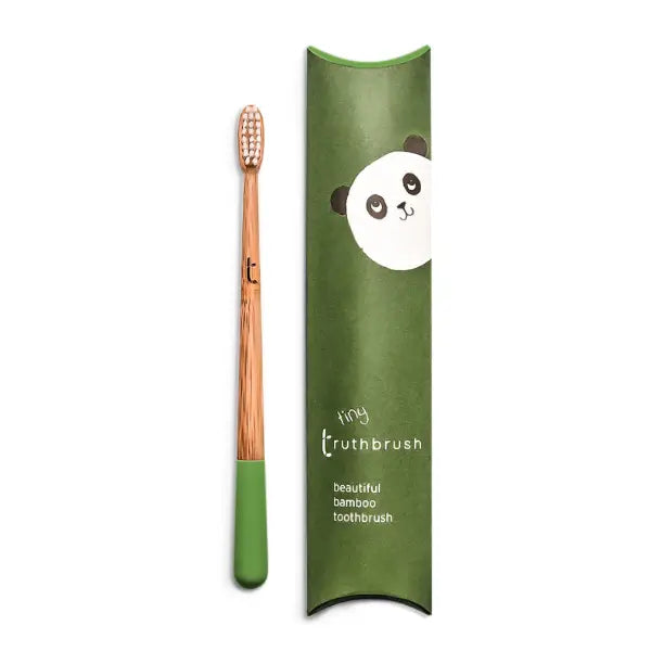 The Truthbrush - Bamboo Toothbrush, with compostable bamboo handle and green bristles, rests next to its green panda-illustrated box labeled "tiny truthbrush beautiful bamboo toothbrush" by Truthbrush.