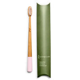 The Truthbrush Bamboo Toothbrush by Truthbrush, featuring soft bristles and a light pink base, is pictured beside a green box labeled "Truthbrush beautiful bamboo toothbrush." The brush is vegan and compostable.