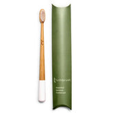 A Truthbrush - Bamboo Toothbrush with white bristles and a white tip is displayed beside a green Truthbrush box labeled "beautiful vegan bamboo toothbrush.