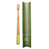 The Truthbrush - Bamboo Toothbrush by Truthbrush is vegan and compostable, with light yellow bristles and handle tip, displayed beside a green case labeled “truthbrush beautiful bamboo toothbrush.”.