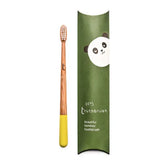 A Truthbrush - Bamboo Toothbrush with a yellow-tipped handle lies next to green packaging featuring a cartoon panda face and the text "tiny truthbrush, beautiful vegan toothbrush.