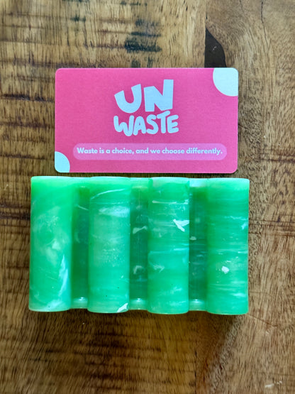 An Upcycled Soap Tray from Unwaste holds a green soap bar and a pink card emblazoned with “Waste is a choice, and we choose differently.” Together, they create an inspiring scene for any zero-waste bathroom.