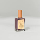 A bottle of BKind Nail Polish by BKind with a tan cap and mauve shade sits against a plain light gray background, featuring a beige label with product details.
