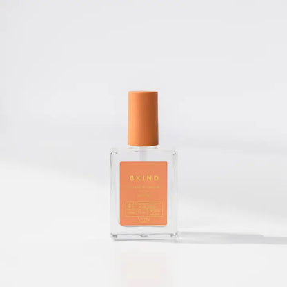 A clear glass bottle of BKind Nail Polish with an orange label and matching orange cap is displayed against a white background with soft shadows. The label features the BKind brand, recognized for plant-based nail polish.