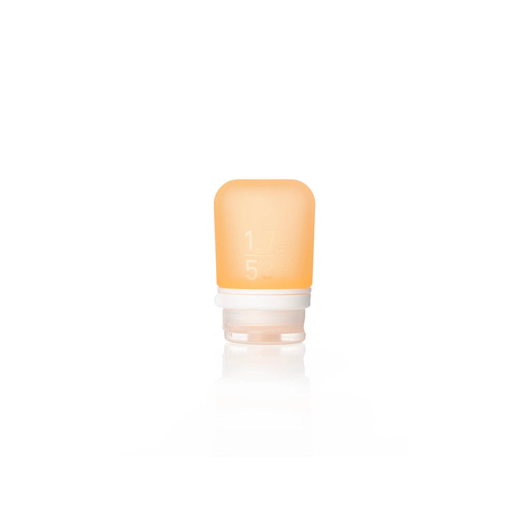 The Humangear GoToob+ is a small, translucent orange silicone travel bottle with a white cap and faint measurement markings. This leak-proof, refillable toiletry container stands upright on a white background.