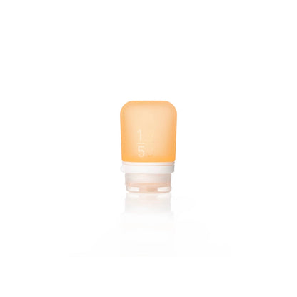 The Humangear GoToob+ is a small, translucent orange silicone travel bottle with a white cap and faint measurement markings. This leak-proof, refillable toiletry container stands upright on a white background.
