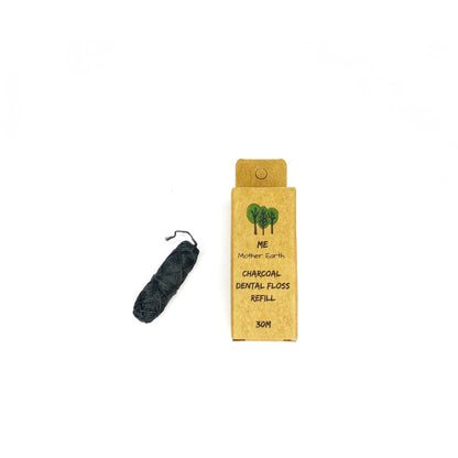 A spool of black Eco Dental Floss by Me.Mother Earth sits next to a brown box labeled "Eco Dental Floss Refill 30M" with a tree illustration, all set against a white background. The vegan floss comes in eco-friendly packaging.