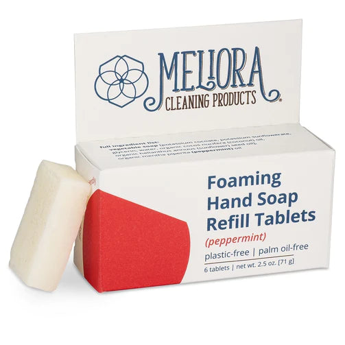 A box of Meliora Foaming Hand Soap Tablets (peppermint) with one white tablet beside it. This plastic-free, palm oil-free soap comes in packaging featuring the brand name and contains 6 refill tablets per box.