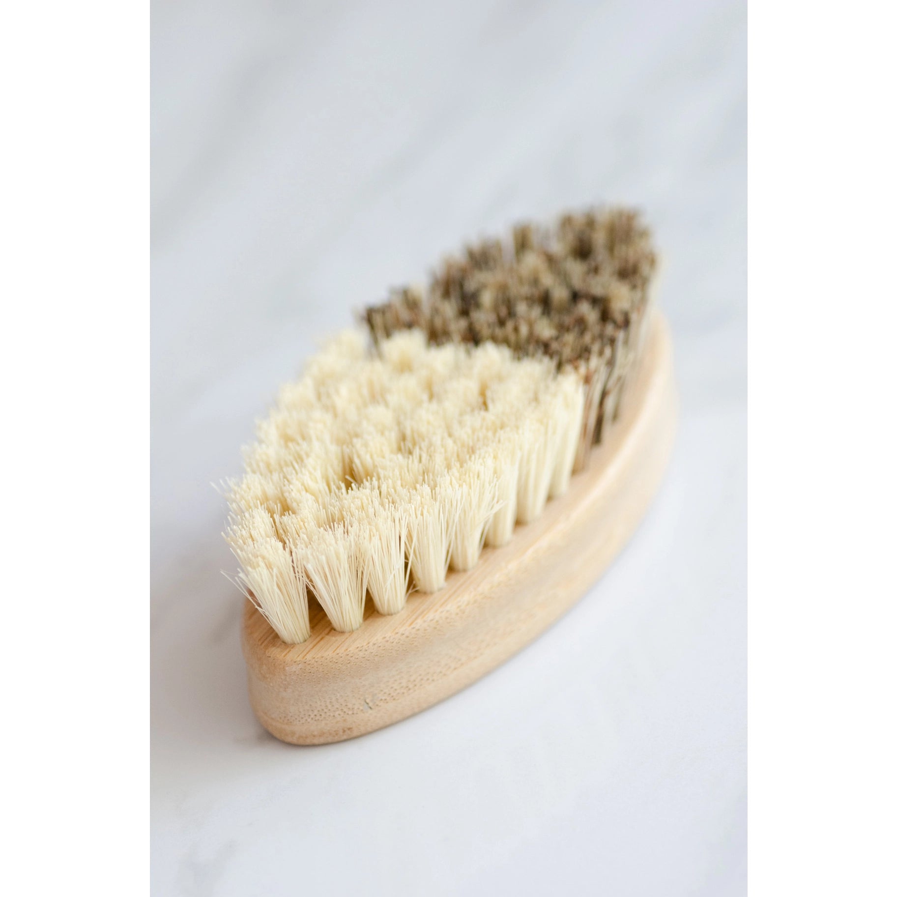 A close-up of the No Tox Life Vegetable Brush featuring two sections: one half with light, soft bristles and the other with darker, coarser bristles—perfectly balanced for cleaning, set against a white background.