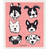 The Cats and Dogs Swedish Dishcloth by Three Bluebirds Swedish Dishcloths features six unique black-and-white cartoon dog faces on a pink background, making eco-friendly cleaning fun and stylish.