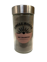 A clear glass jar with a metal lid labeled Swell Roots Dry Shampoo features a sunburst design and pink half-circle, highlighting this all-natural product with ingredient details listed at the bottom.